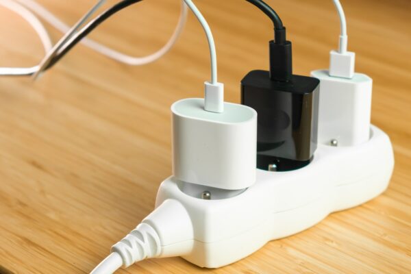 The electrical extension strip with connected white and black power plugs on the wooden table. Smart