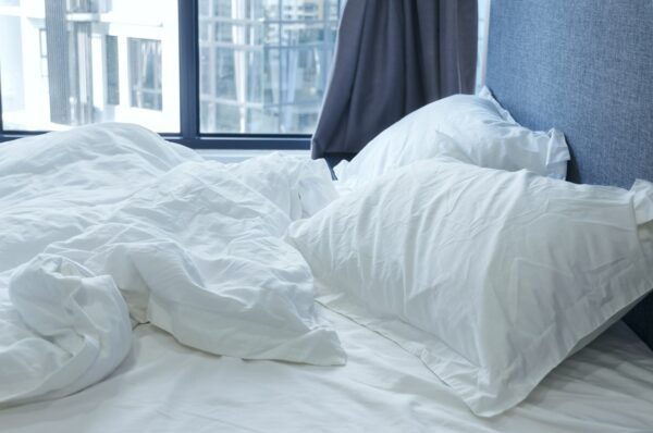 Zerknittertes Bett mit weißer Bettwäsche